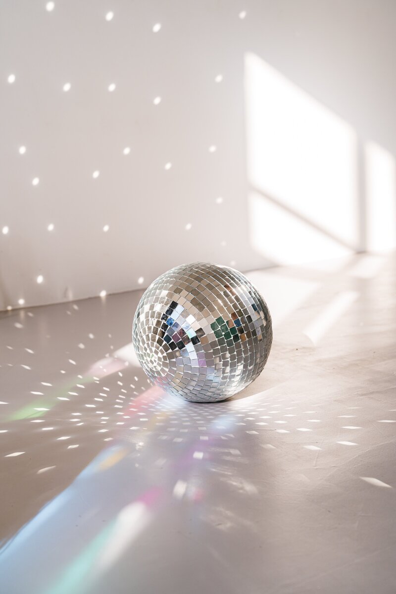 Disco balls of different sizes with a woman’s foot with a heel on the largest one