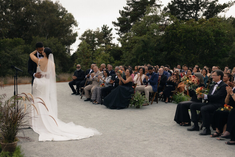 Bride and groom sharing their first kiss during the wedding ceremony, captured in a candid, photojournalistic style with a mix of digital and film photography, showcasing an authentic and emotional moment