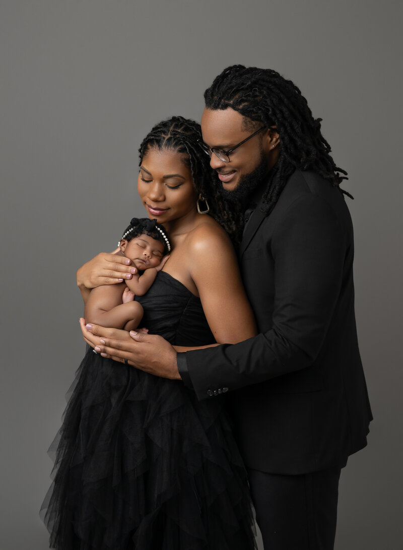 Baby on Mom's chest being snuggled by Mom and dad. Photo taken by Jenni Nikki at Marietta Photo studio.