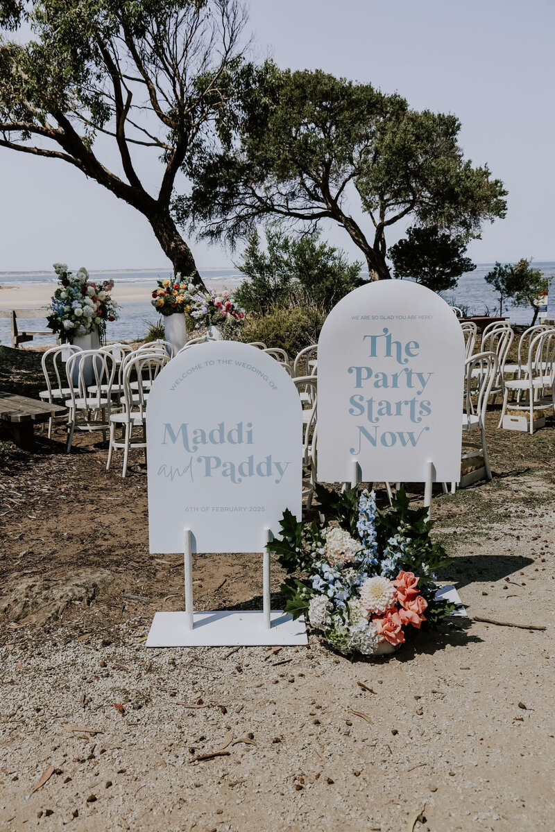 Personalised wedding signage at entry to wedding ceremony with floral arrangement