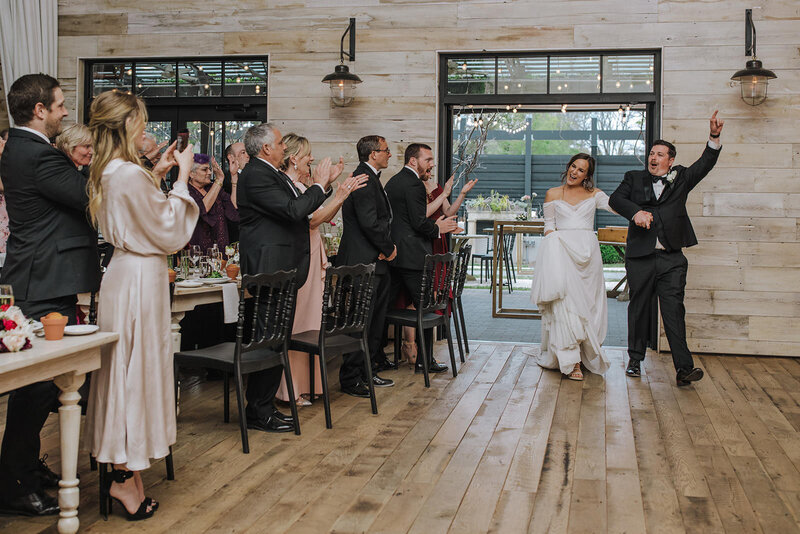 A couple celebrating and walking into their wedding reception.