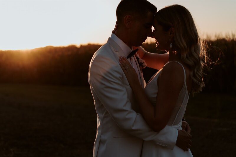 A bride and groom hugging at sunset being photographed by Waikato Wedding Photographer Haley Adele during their Narrows Landing Wedding