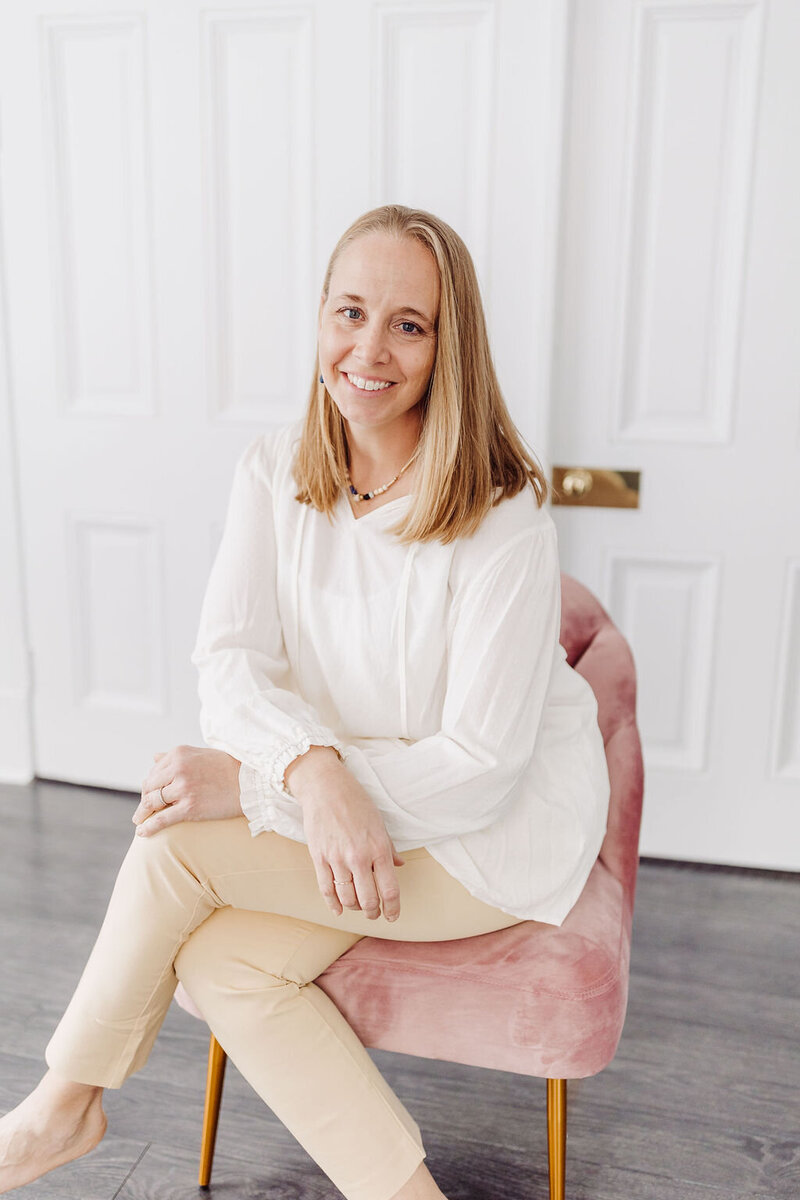 photographer smiling and sitting in a pink chair
