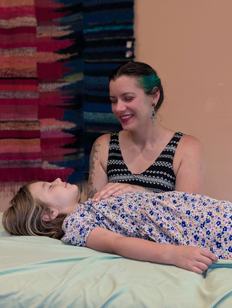 Young child receiving craniosacral therapy from Julie Pokorny in Baltimore, Maryland while they're both smiling. 