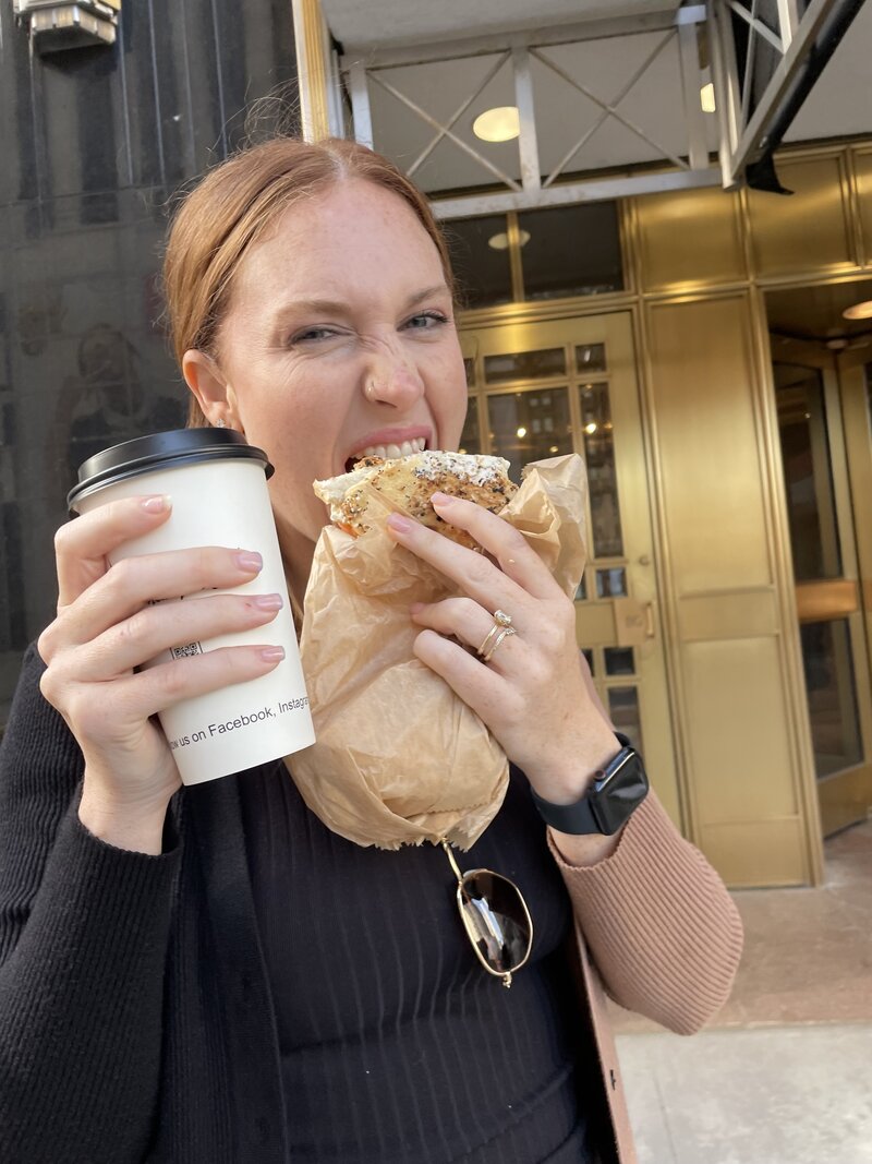 Girl eating a Bagel and holding a coffee in Manhattan, New York