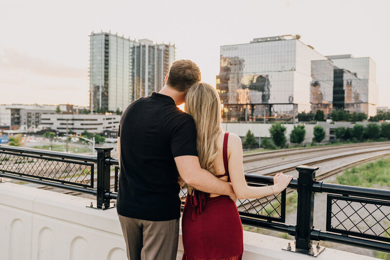 Man embracing his fiancée while overlooking the downtown Nashville, TN, skyline during their engagement session.