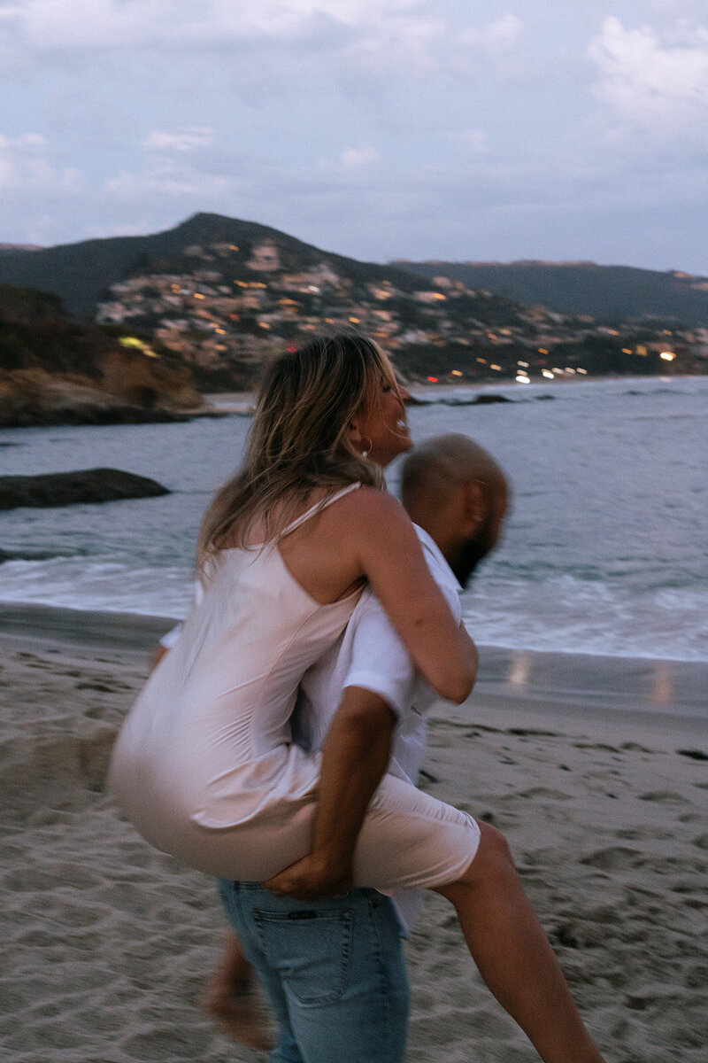 a couple piggy back riding on the beach during a documentary couples session