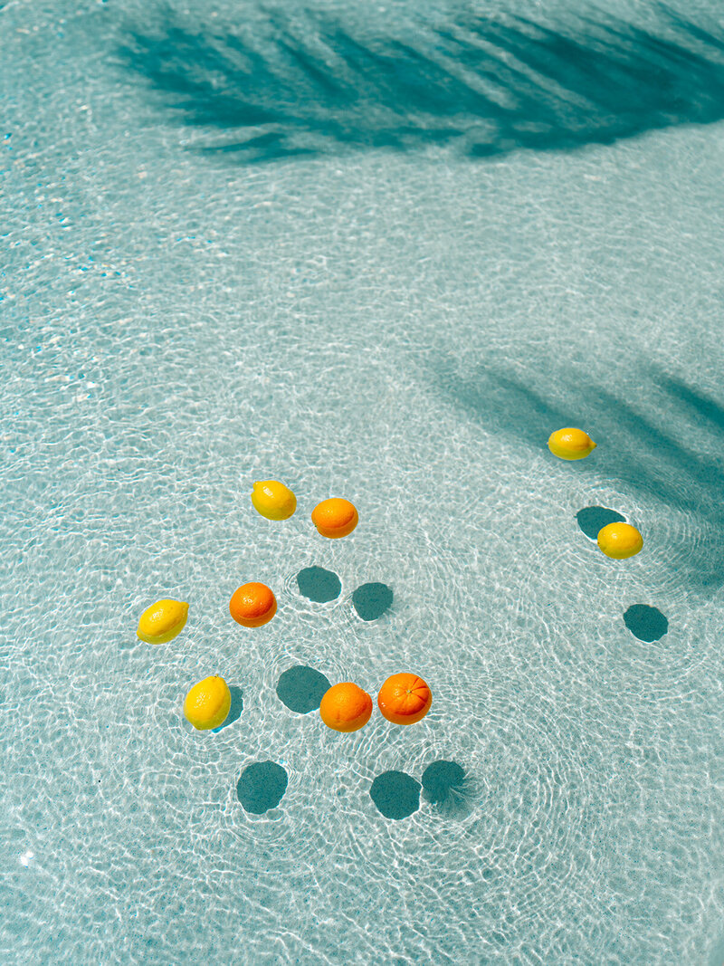 Lemons and oranges floating in pool water