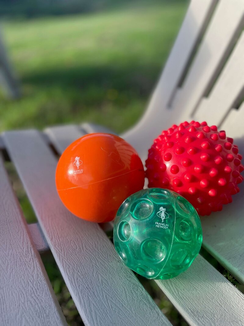 Three Franklin Method balls lie on a chair outside.