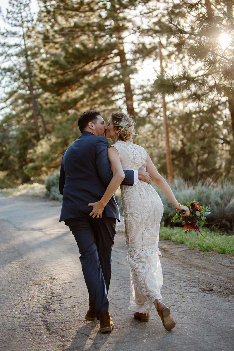 A couple with their arms around each other walking as they kiss