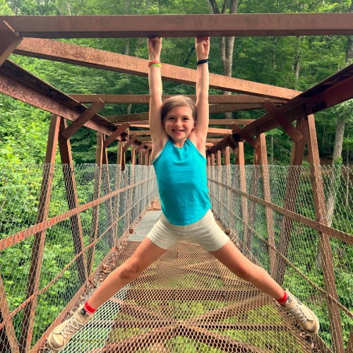 Girl hanging from bridge smiling