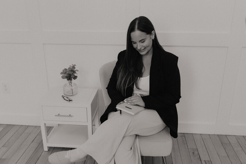 A girl poses smiling looking at a notebook during her branding photoshoot in Peterborough, Ontario. 
