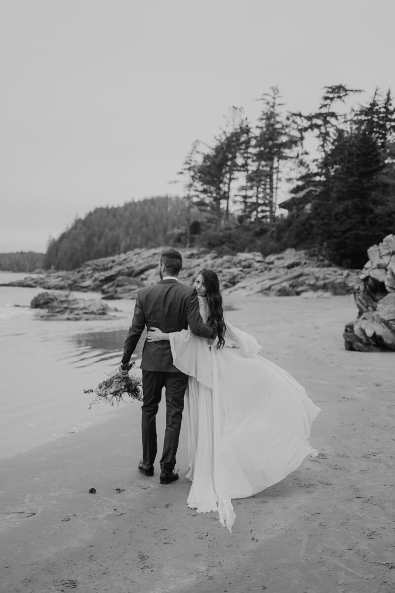 A couple walks together on the beach on their elopement day in Tofino BC