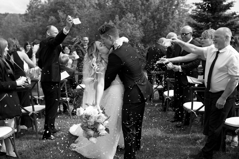 Couple walk down the aisle and kiss with flower confetti
