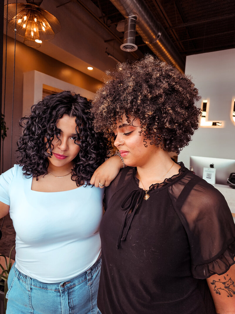 Two clients show off their big curly styles with tight coils and big loose curls