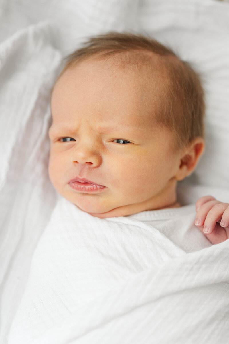 a wide eyed baby all swaddled up