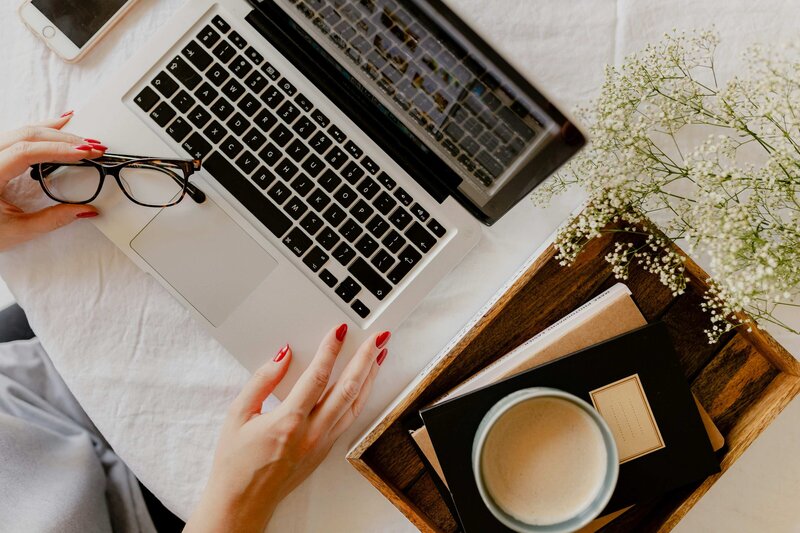 Laptop, smartphone, and latte on a light wood desk, styled in soft natural lighting for a cozy work-from-home vibe