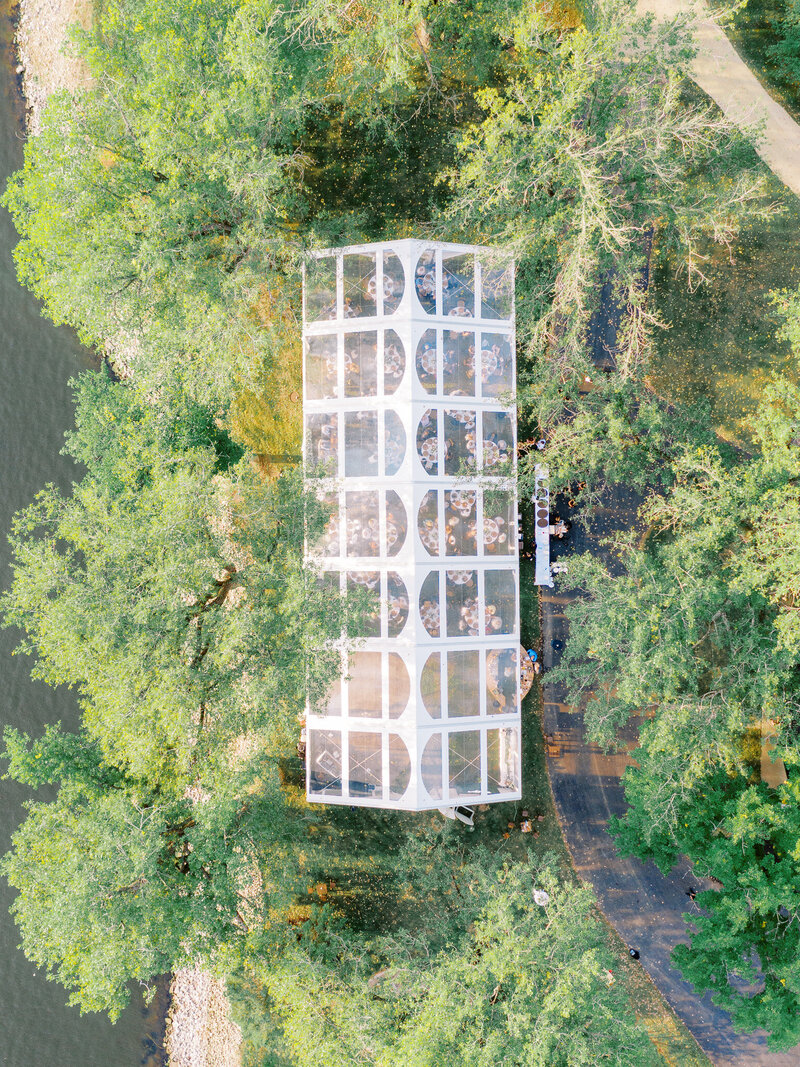 Drone photograph of clear tent with wedding guests inside the tent