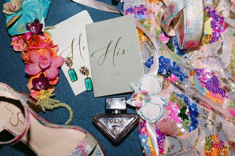 A colorful sequined veil, high heels, perfume bottle, vow books, and jewelry