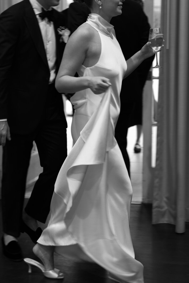 A bride lifts the hem of her satin sheen wedding dress.