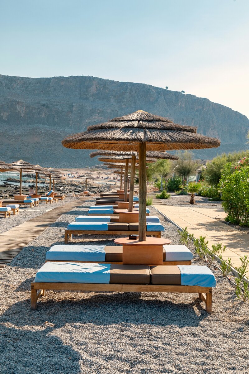 Wooden beach beds with straw beach umbrellas on a sandy beach
