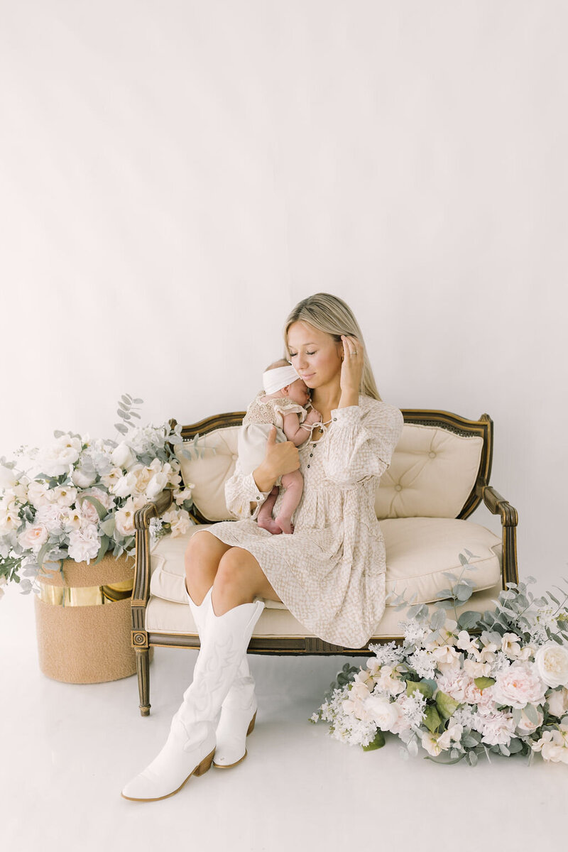 Outdoor senior portrait of a girl in a cream dress and cowboy boots walking along a wooden fence, captured by Raleigh Senior Photographer Lindsey Lambert Photography.