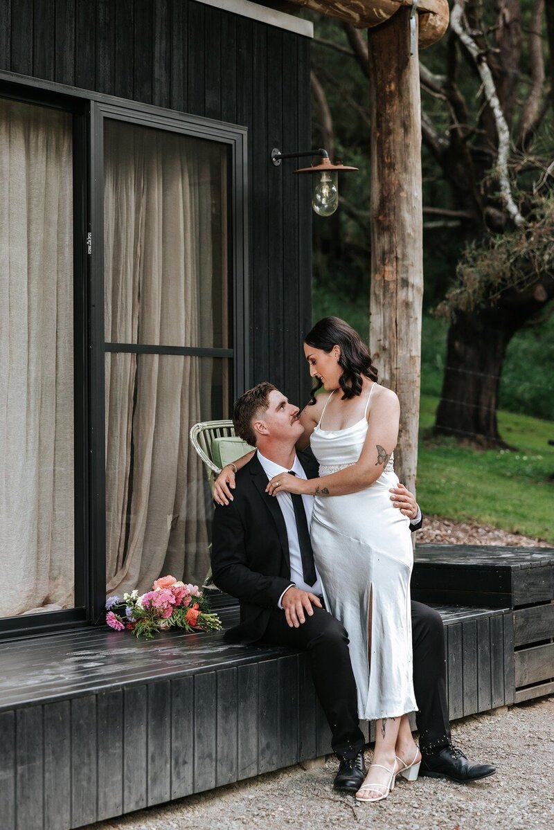 A black and white image of a rustic barn set up for a wedding reception with a wall of wine barrels and a ceiling full of twinking fairy lights
