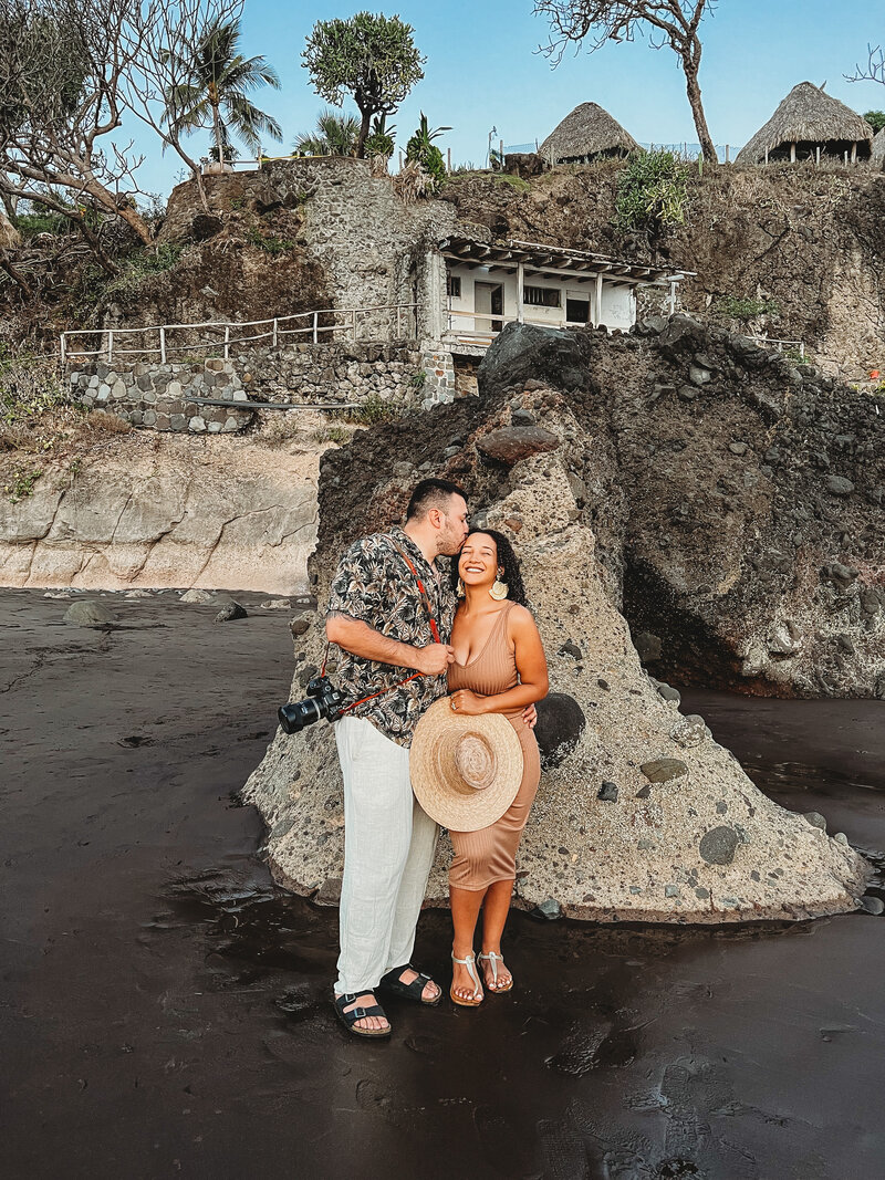 husband kissing wife on the beach