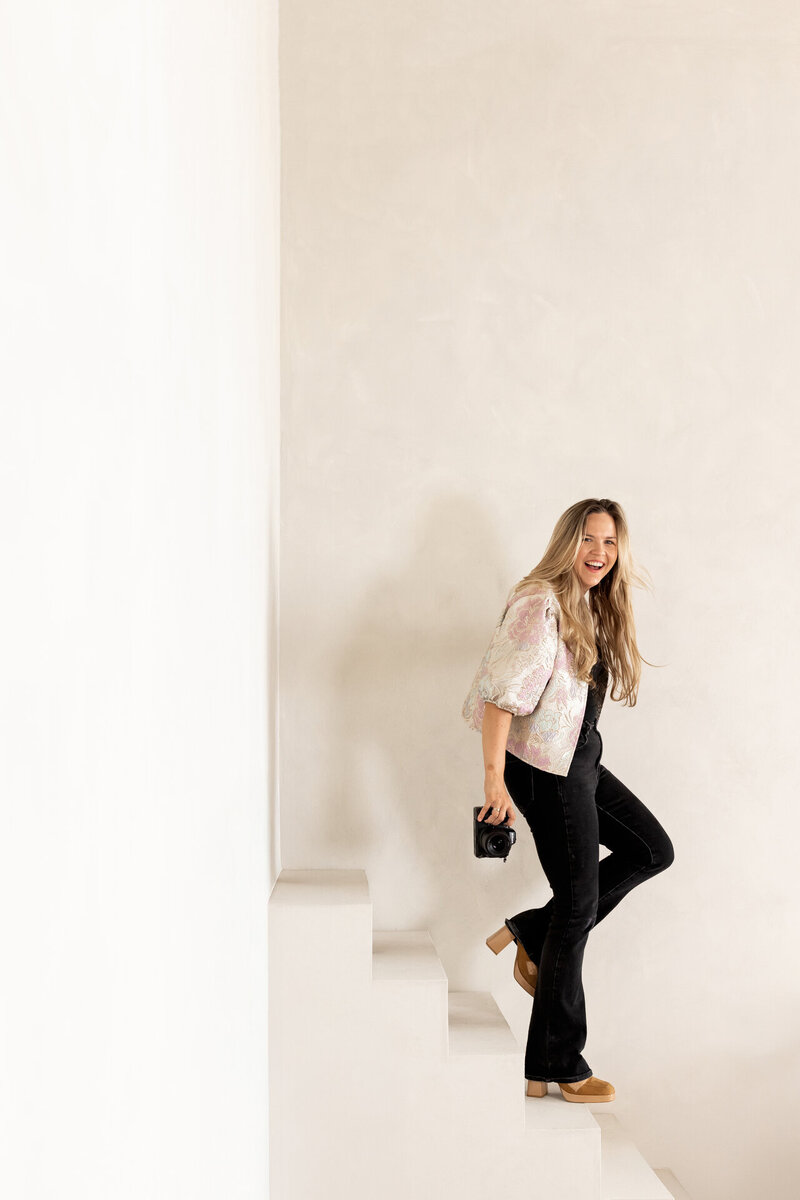 Juliette Laurant loopt elegant de trap af in Studio Laurant en kijkt recht in de camera tijdens een branding fotoshoot.