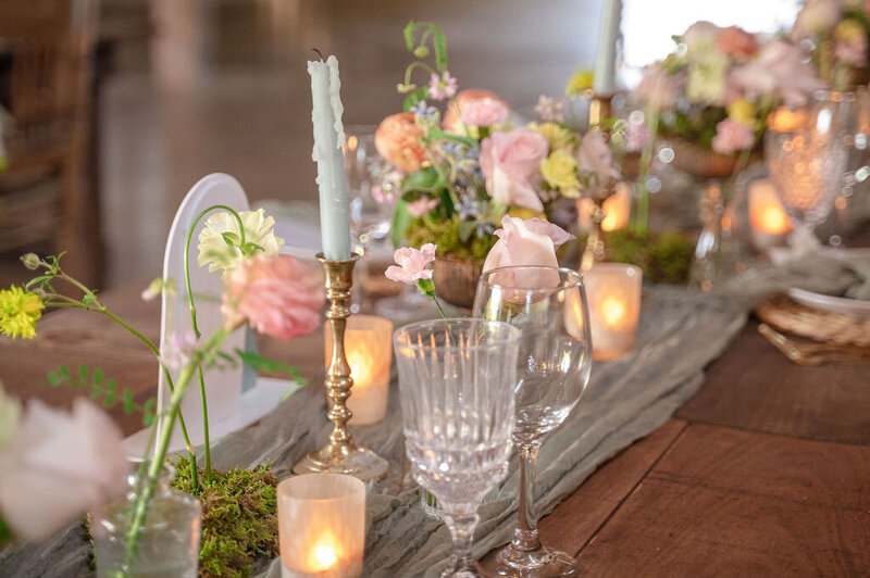 Close-up of wedding table decor with flowers, candles, and glassware.