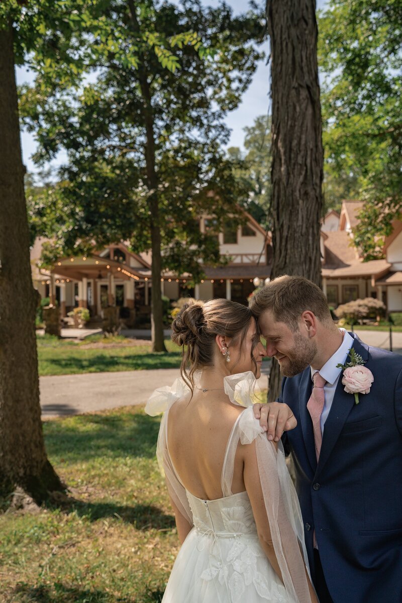 Bride and groom touch foreheads under tall trees on their wedding day at Lizton Lodge, Indiana