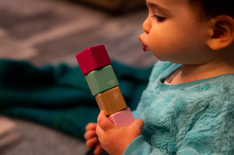 A baby is playing with a colorful block toy.
