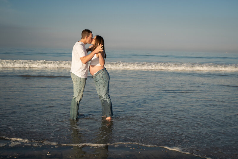 Couple holding hands and kissing  on the beach in San Diego, California