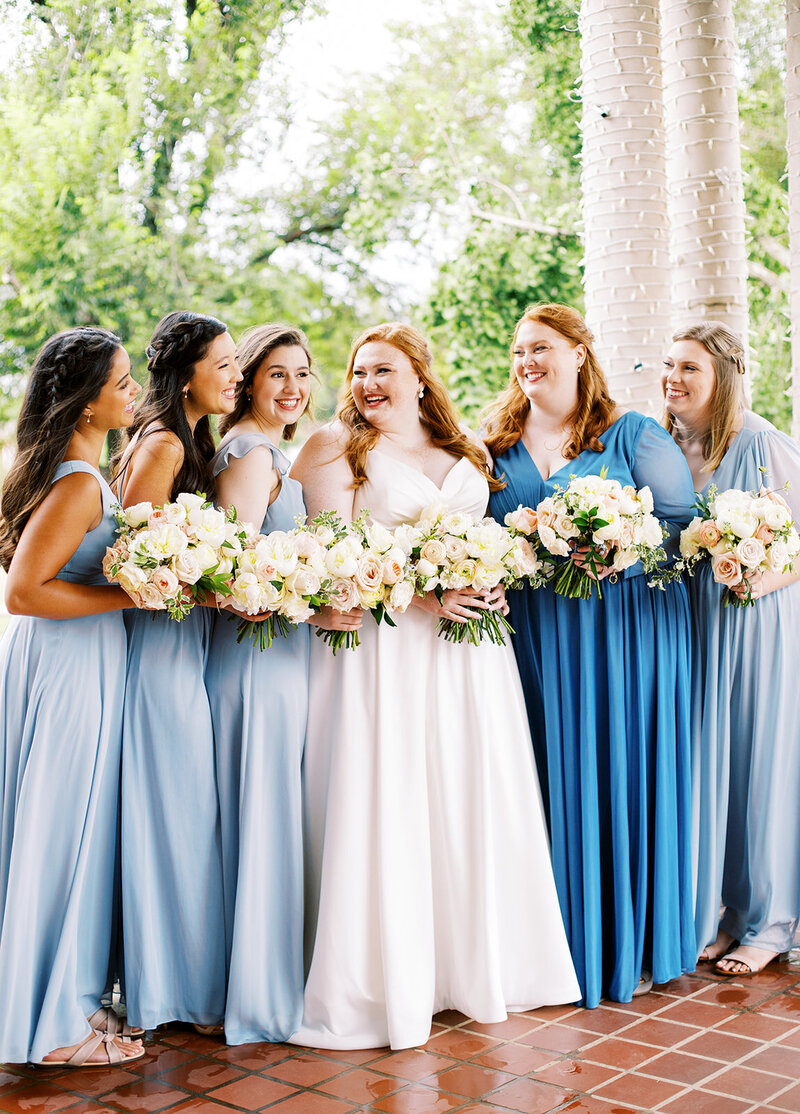 A bride looking at her bridesmaids holding bouquets