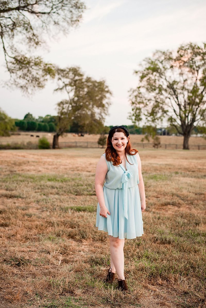 Wedding planner wearing a mint dress smiling at the camera in a field