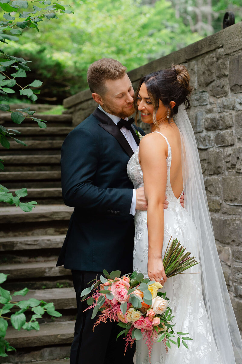 a groom kissing his bride on her cheek taken outdoors at Eaton Hall by Ottawa wedding photographer JEMMAN Photography