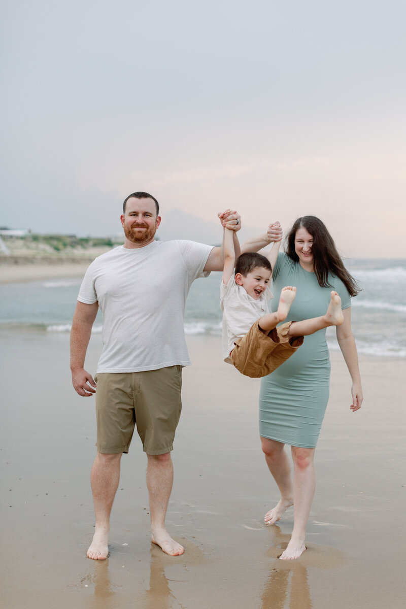 A family wearing teal and white walk the beach during their portrait session