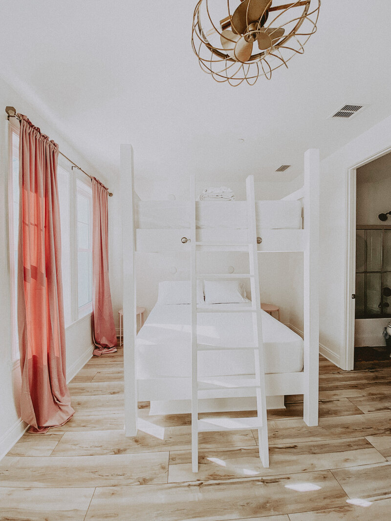 white bedroom with bunkbeds and pink curtains