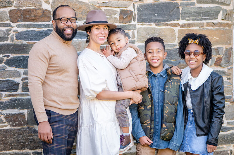 A family poses for portraits in front of a brick wall