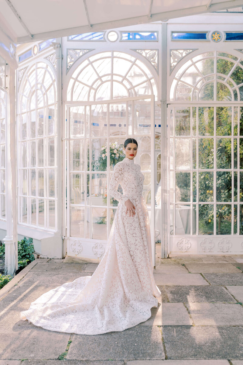 a bride in a long sleeved lace wedding dress standing outside the orangery at avington park for a wedding planned by westacott weddings and events