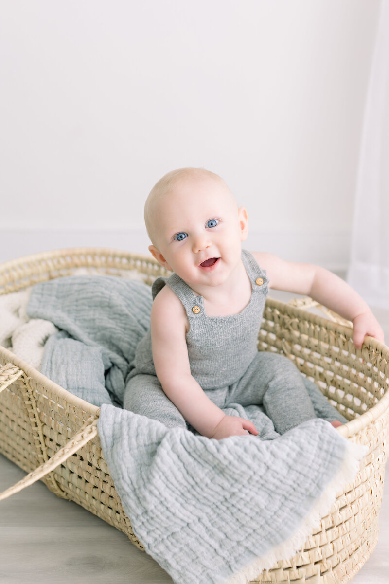 baby sitting in moses basket by philadelphia newborn photographer