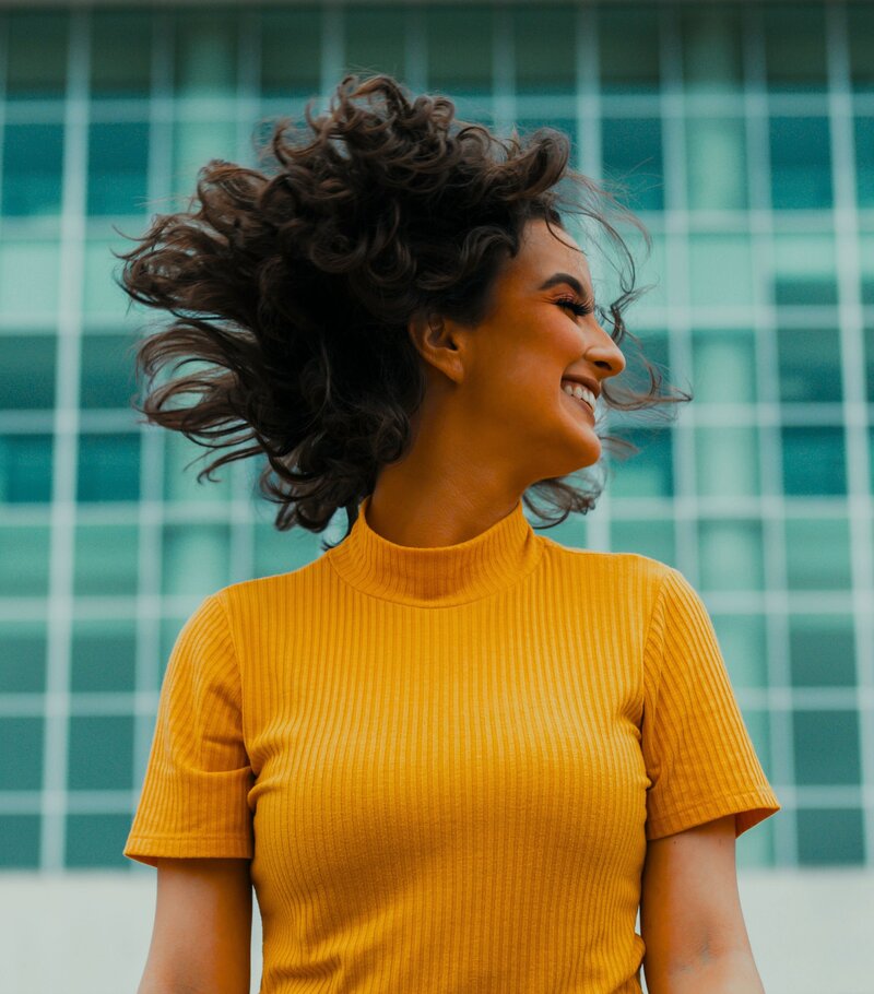 Woman in an orange shirt flipping her hair around