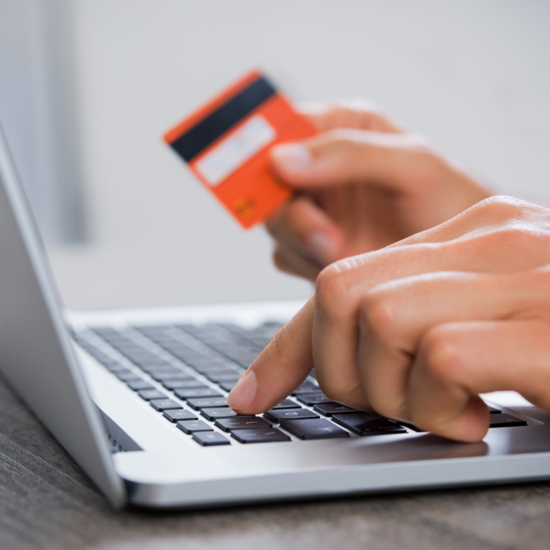 Hand holding a credit card and typing on computer shown to represent Ecosystems online bill pay option