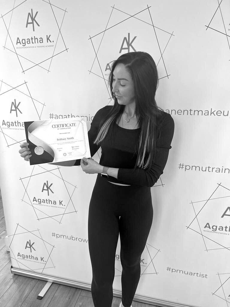 Brittany Smith, Owner of Vamp Cosmetic, holding permanent makeup certification certificate