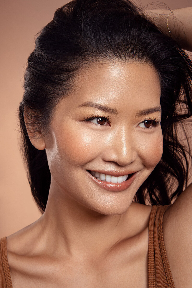 Danielle Yu in a glowing beauty portrait, featuring soft curls and a vibrant smile, captured by Ylva Erevall.