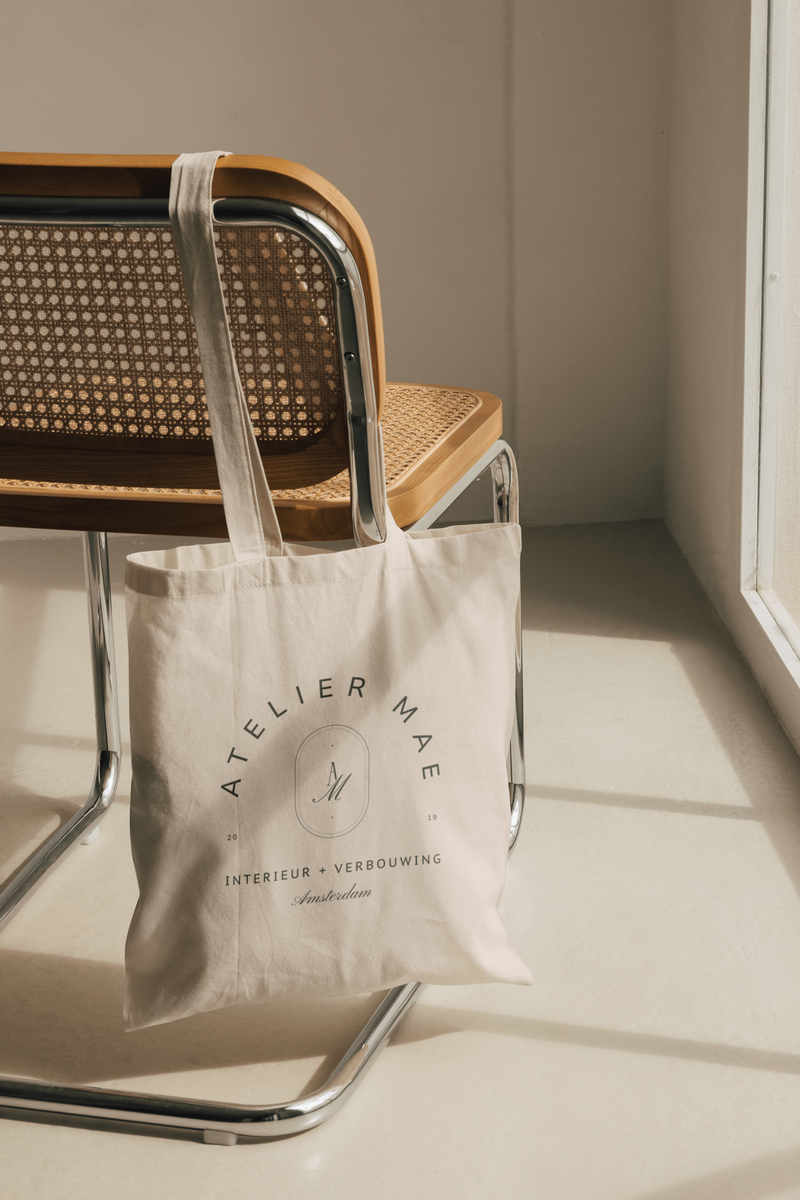 Logo atelier mae op totebag hangend over stoel