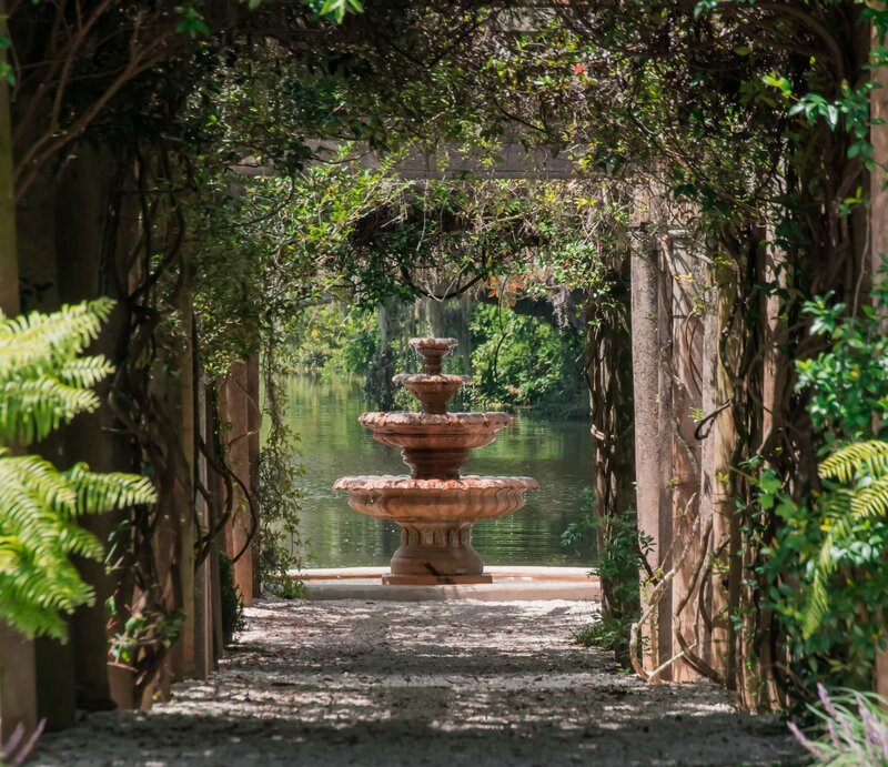Stone fountain framed by vine-covered pergola at Airlie Gardens, a historic Wilmington NC wedding venue