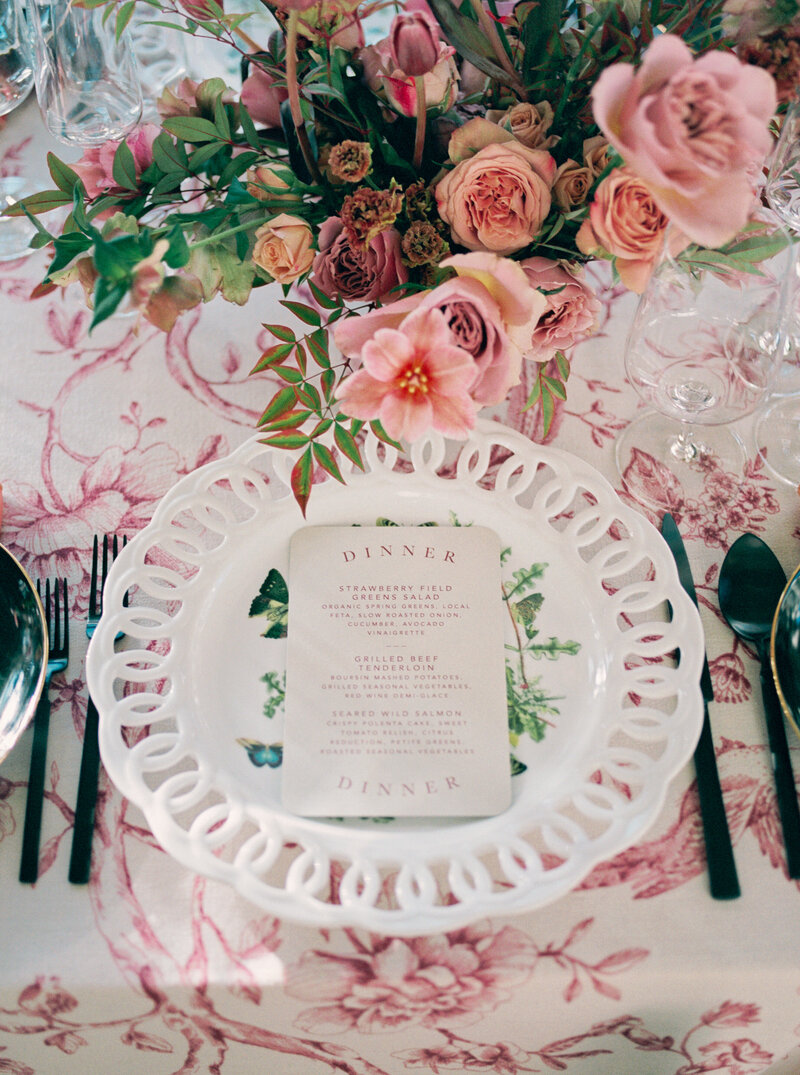 Elegant wedding table setting at Prospect Park Boathouse in Brooklyn, NYC, featuring a white lattice charger plate, floral dinner menu, and vibrant pink and blush centerpiece on a patterned tablecloth, captured by Stephanie Michelle Photography, a luxury wedding photographer.