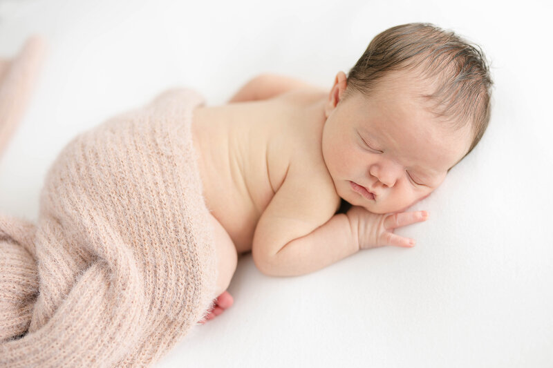 newborn baby napping while wrapped in a blanket