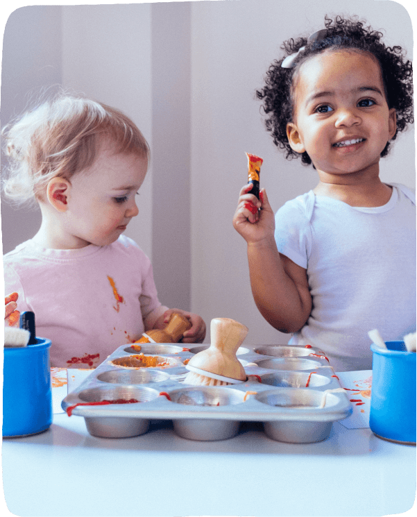 two little girls at a table playing with baking tools